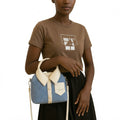Person holding a blue and beige handbag against a white background