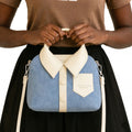 Blue and white handbag designed like a shirt with collar and buttons, held by a person.