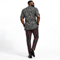 Man wearing a patterned shirt and striped pants on a white background