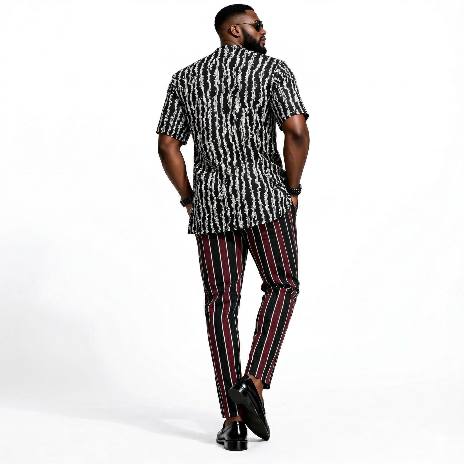Man wearing a patterned shirt and striped pants on a white background
