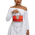Woman in a white dress holding a red handbag with pearl details on a white background