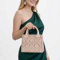 Woman in a green dress holding a beaded handbag against a white background
