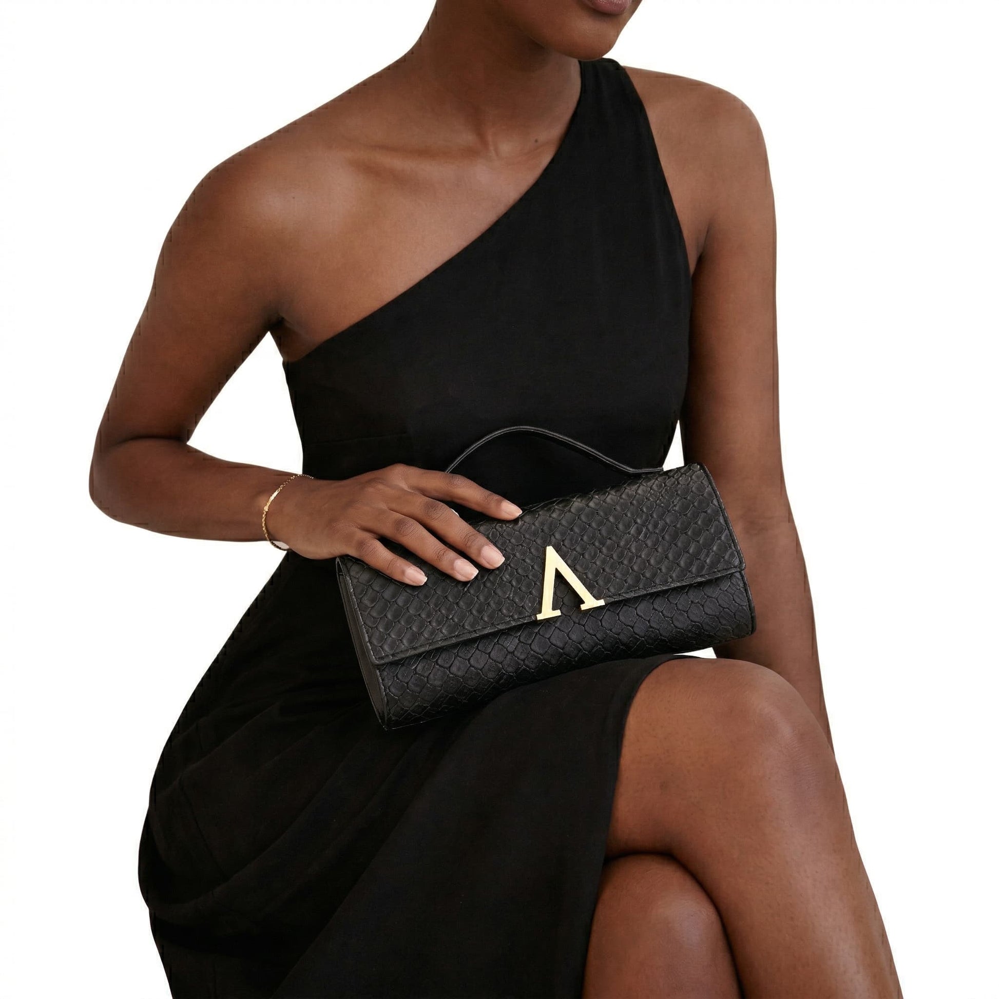 Woman holding a black clutch with a gold emblem on a white background