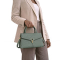 Person holding a green handbag with a neutral background