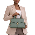 Person holding a green handbag against a white background