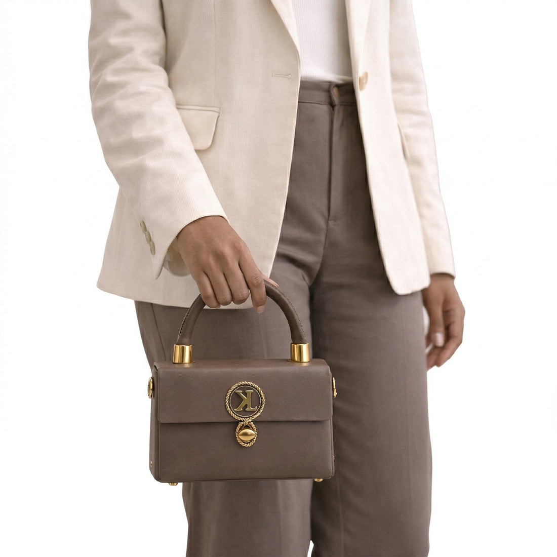 Woman holding a brown handbag with gold accents against a white background
