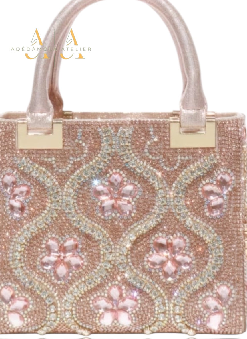 Rose gold handbag with floral pattern and crystals on a white background