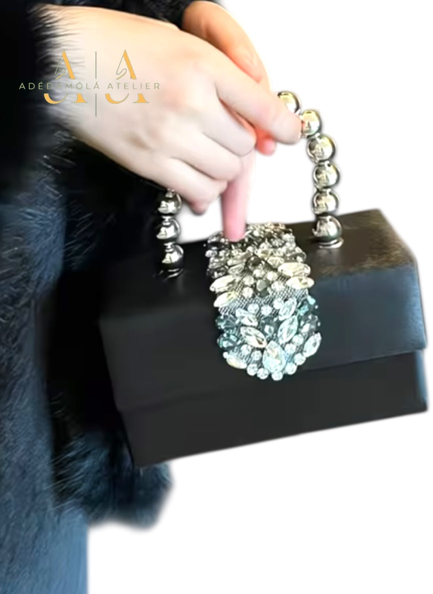 Red clutch bag with decorative  and beads held by a person wearing a fur coat.