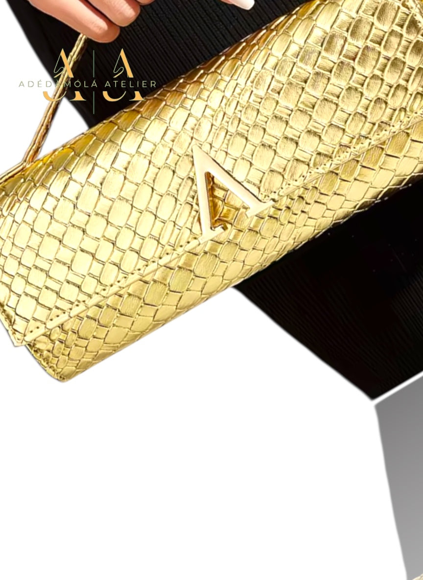 Black textured clutch bag with gold letter 'A' on a reflective surface