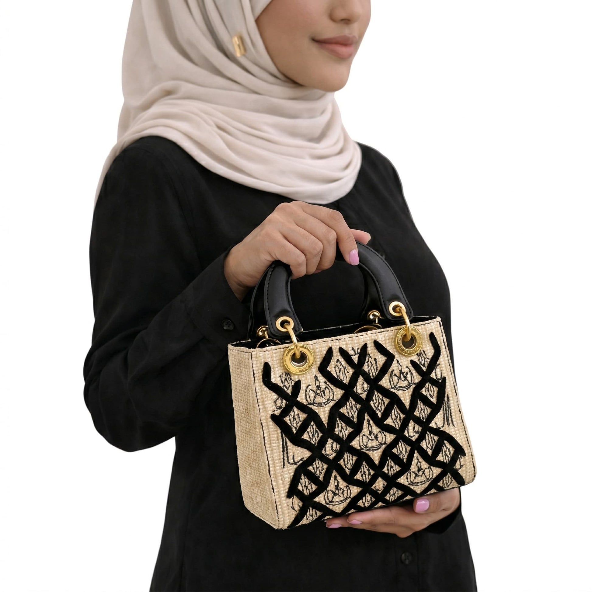 Person holding a decorative handbag with intricate patterns on a white background