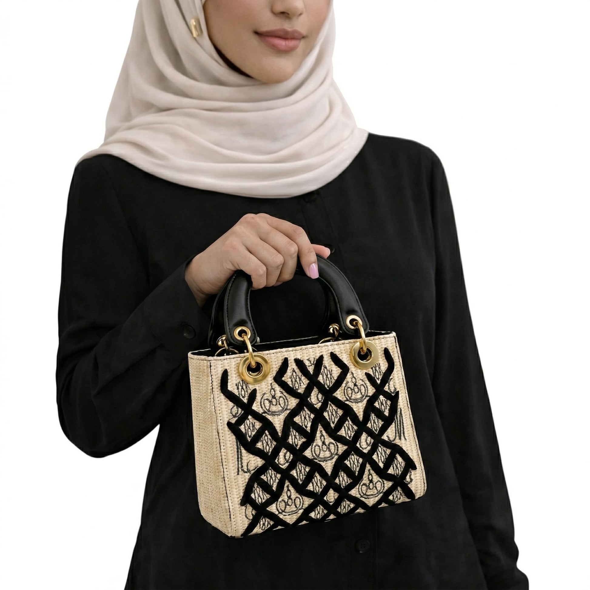 Person holding a decorative handbag with intricate patterns on a white background