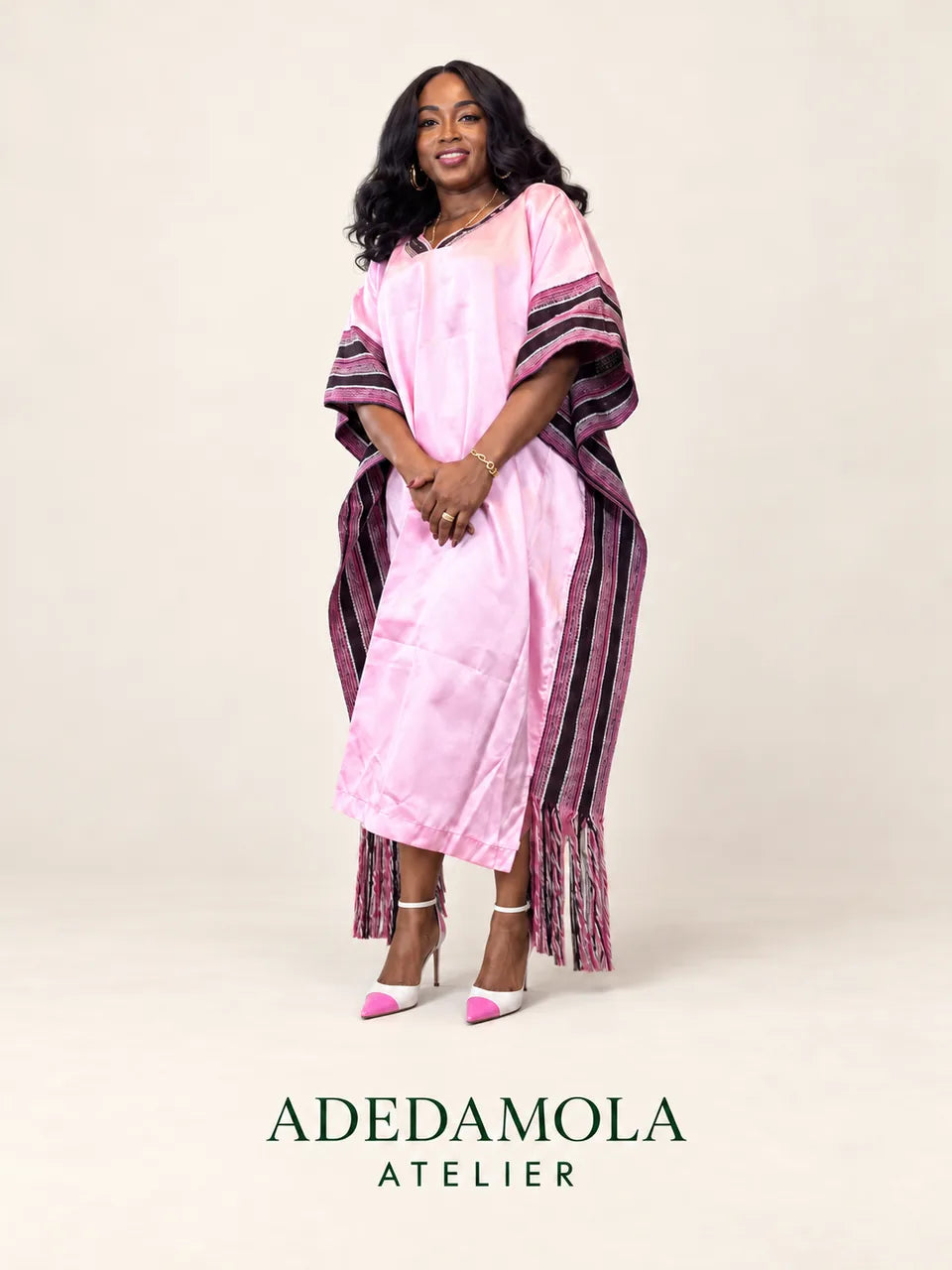 Model wearing a pink Adedamola Atelier outfit with striped details, against a warm ivory background.