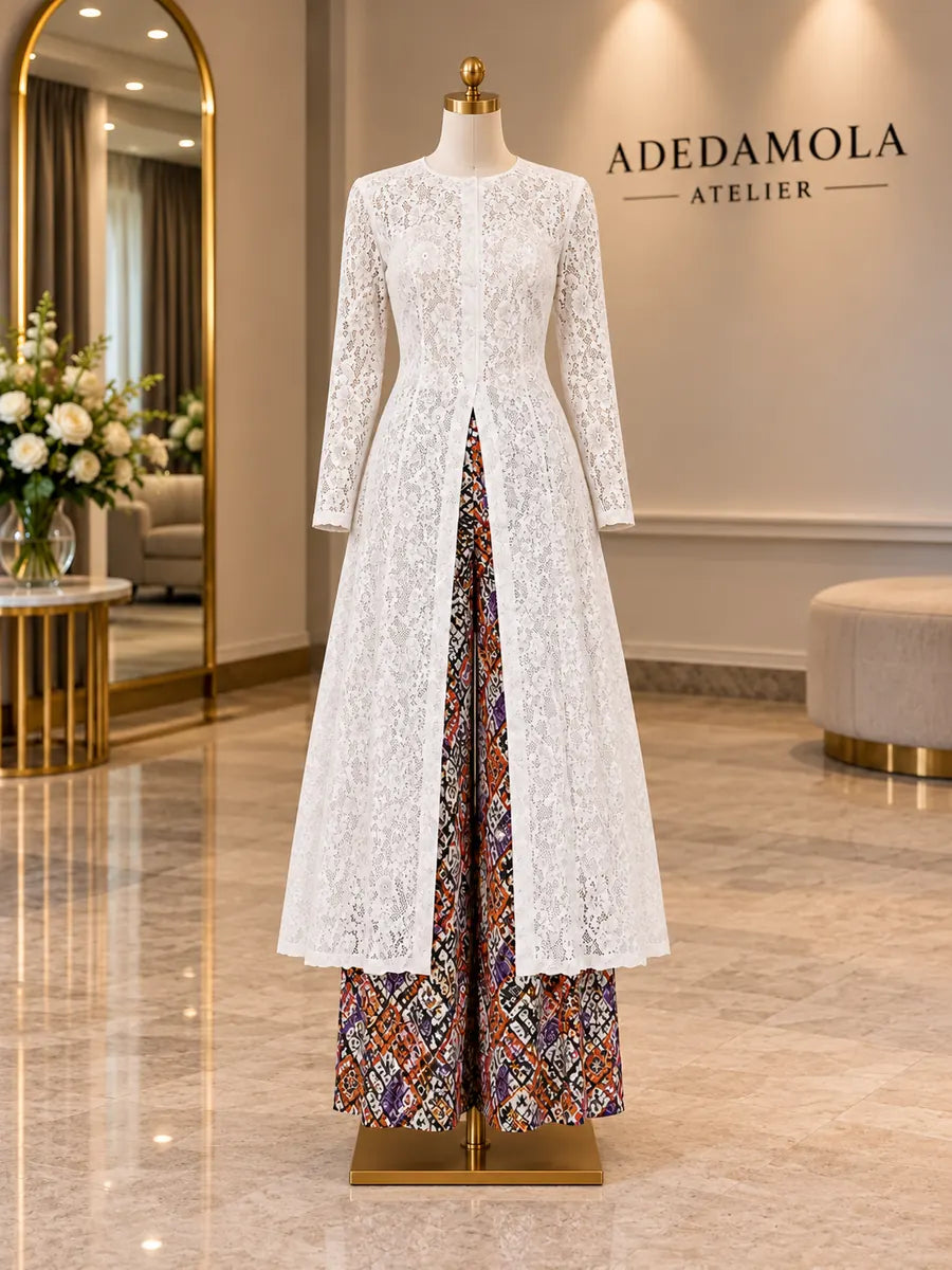 Full-length white guipure lace duster worn open over patterned wide-leg trousers