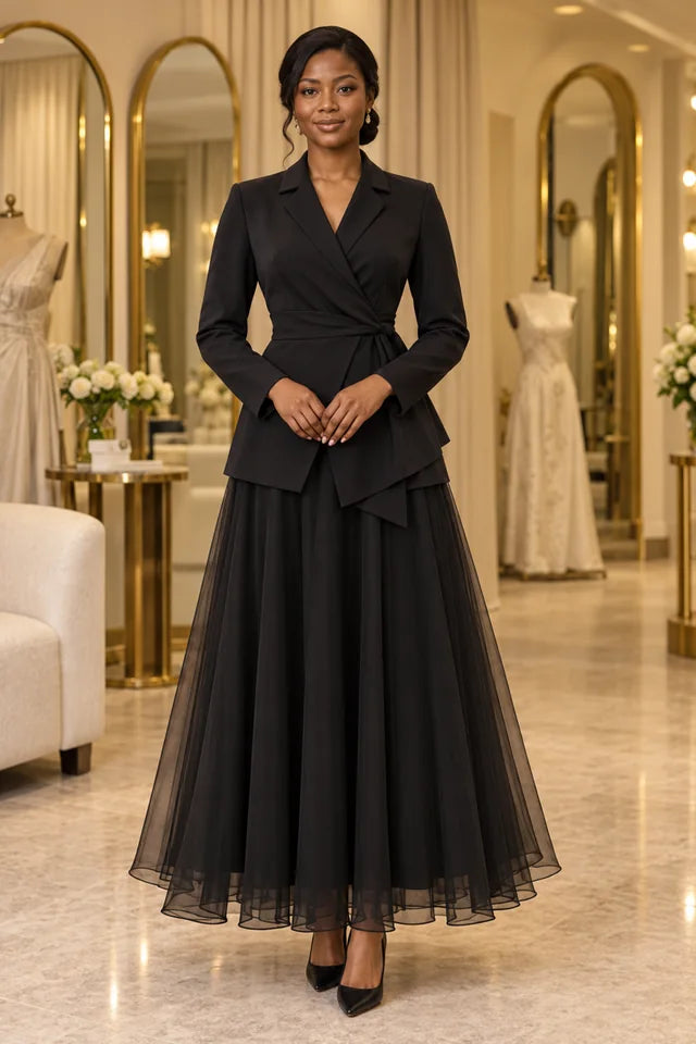 Woman wearing a black wrap jacket with an asymmetric peplum and a flowing sheer skirt.